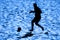 Silhouetted  beach soccer action of male player on sand.Blue color filter
