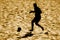 Silhouetted  beach soccer action of male player on sand.Yellow color filter
