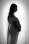 A silhouetted, black and white image of a heavily pregnant woman wearing a sheer dress