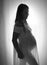 A silhouetted, black and white image of a heavily pregnant woman wearing a sheer dress