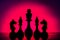 Silhouetted chess pieces against a red gradient background