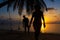 Silhouetted couple in love walks on the beach during sunset