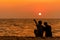 Silhouetted couple sitting, and relax on beach in love and embrace, sunset in the beach.