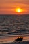 A silhouetted couple watch the sunset at the beach.