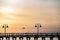 Silhouetted dock and lamp poles in front of beautiful orange sunset background