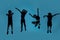 Silhouetted full length shot of four little sportive kids looking joyful while posing, jumping isolated over blue