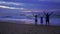 Silhouetted happy asian family standing on beach at sunset or sunrise raising arms having fun on the beach at sunset in Slow Motio