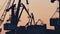 Silhouetted harbor cranes loading freight during golden hour