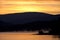 Silhouetted hills around Shuswap Lake and colorful orange sky, British Columbia