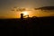 Silhouetted individual rides a bicycle atop a hillside at sunset