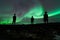 Silhouetted male figures looking up at the beautiful Aurora Borealis in the night sky