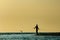 A silhouetted man fishes at sunset along Barefoot Beach, Florida