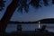 Silhouetted Muskoka Adirondack Chair on a Dock Beside a Lake