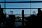 Silhouetted passangers waiting at an airport terminal. Full length shot of woman standing at terminal and waiting for