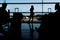 Silhouetted passangers waiting at an airport terminal. Full length shot of woman standing at terminal and waiting for