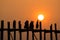 Silhouetted people on U Bein Bridge at sunset.