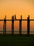 Silhouetted person on U Bein Bridge at sunset, Amarapura, Myanmar