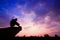 Silhouetted photo. Lonely man sitting on cliff.