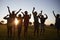 Silhouetted school kids jumping outdoors at sunset