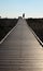 Silhouetted sixty year old man walking across the end of a wooden pathway