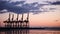 Silhouetted tanker cargo ship boat sailing into a port with cranes at sunset or sunrise