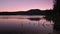 Silhouetted trees and pink sky reflect in Sparks Lake Oregon.