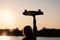 Silhouetted Woman posing with her hands holding skateboard raised up in the sunset sky