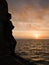 Silhouetted young man watches sunrise from a pier.