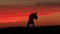 Silhouettes of the adorable couple tenderly kissing while dancing over the red sky during the sunset.