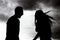 Silhouettes of arguing couple against sky with rainy clouds. Relationship problems