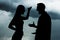 Silhouettes of arguing couple against sky with rainy clouds. Relationship problems