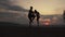 Silhouettes of athletic mixed gymnastic couple doing exercises on the mountain peak. Grace and beauty of human\'s body