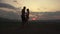 Silhouettes of athletic muscular couple of fitness instructors dancing on sunset on the mountain peak. Beautiful cloudy
