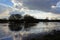 Silhouettes of bare shrubs and trees and dark clouds reflecting in the water