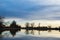 Silhouettes of Bare Trees at Sunrise by a Lake