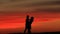 Silhouettes of the beautiful happy couple softly kissing over the red sunset.
