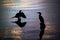 Silhouettes of birds resting on wooden pier residues in a lake d