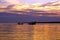 Silhouettes of boats with fishermen fishing at dusk sunset