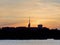 Silhouettes of buildings with reflection of light on lake at dawn break