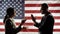 Silhouettes of business people man and woman arguing about something and gesturing against the background of the American flag