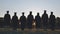 Silhouettes of college graduates standing in a meadow.