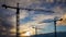 Silhouettes of construction cranes on the background of a beautiful sunset sky.