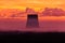 The silhouettes of the cooling towers of thermal power station among the forest on the background of scarlet sunrise or sunrise