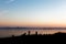 Silhouettes of a couple on a lake shore, taking photos of sunset