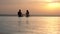 Silhouettes, couple in love, man and woman, sitting holding hands in outdoor infinity pool with panoramic sea view, at