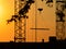 Silhouettes of a crane and construction worker on a sunset background