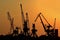 Silhouettes of cranes for loading containers onto freighters/cargo ships in the port at sunset