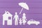 The silhouettes cut out of paper of man and woman with one girl under the umbrella, house and car near