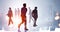 Silhouettes of diverse walking business people working and looking for solutions in abstract office space with sunset New York