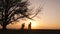 Silhouettes of family holding the hands and running in the meadow during sunset.